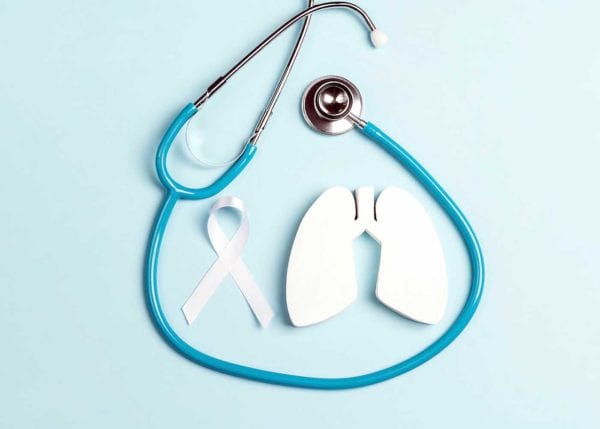 An image of a stethoscope, a white lung cancer ribbon and a white paper cut out in the shape of a pair of lungs