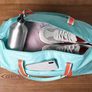 Open blue duffle bag showing water bottle, blanket and comfortable shoes, which may be included in a chemotherapy bag.