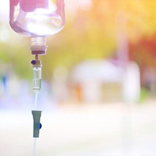 A bag of mesothelioma immunotherapy drugs hangs from an IV stand in front of a window.