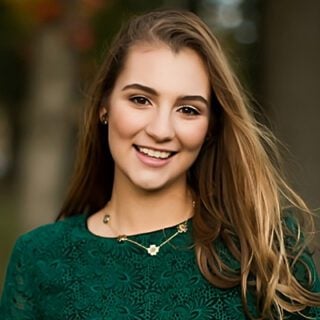 A photo of 2023 Mesothelioma Scholarship winner, Isabella Toth. She has long, dark blonde hair and is wearing a dark green lace shirt.