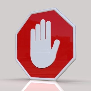 A large stop sign bearing a centered hand icon sits in the center of a white room with a white floor, reminding viewers that data shows asbestos should be banned.